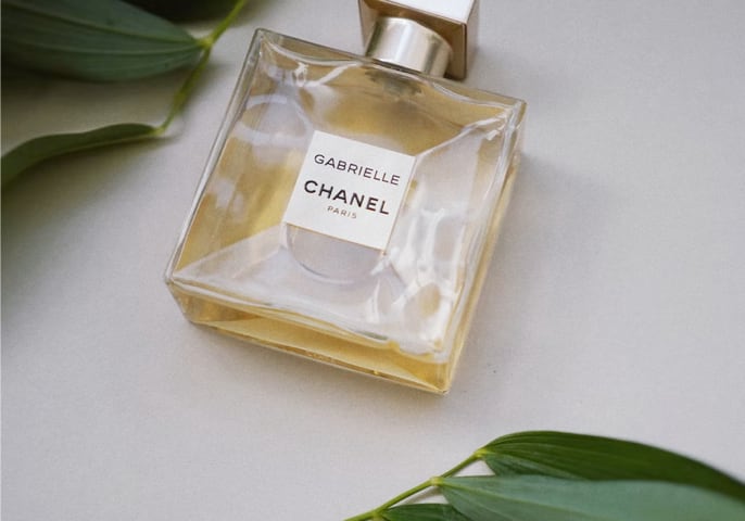 Gabrielle chanel paris perfume bottle laying on a surface with decorative plants